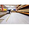 young man carpenter measuring wooden board for cutting while working in big modern carpentry High quality wood concept
