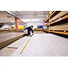 young man carpenter measuring wooden board for cutting while working in big modern carpentry High quality wood concept