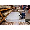 young man carpenter measuring wooden board for cutting while working in big modern carpentry High quality wood concept