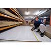 young man carpenter measuring wooden board for cutting while working in big modern carpentry High quality wood concept