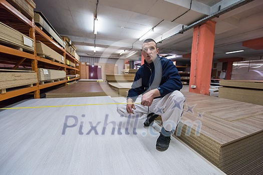 young man carpenter measuring wooden board for cutting while working in big modern carpentry High quality wood concept young man carpenter measuring wooden board for cutting while working in big modern carpentry High quality wood concept