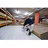 young man carpenter measuring wooden board for cutting while working in big modern carpentry High quality wood concept