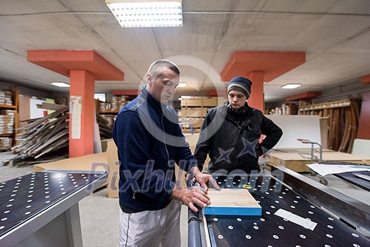 two young carpenters calculating and programming a cnc wood working machine in workshop. wood workers preparing a computer program for CNC machine at big modern carpentry two young carpenters calculating and programming a cnc wood working machine in workshop. wood workers preparing a computer program for CNC machine at big modern carpentry