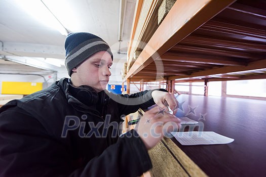 young man carpenter using pen while writing a receipt in big modern carpentry young man carpenter using pen while writing a receipt in big modern carpentry