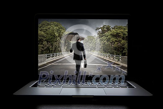 Small businessman with umbrella walking in to laptop screen. Mixed media Small businessman with umbrella walking in to laptop screen. Mixed media