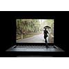 Small businessman with umbrella walking in to laptop screen. Mixed media