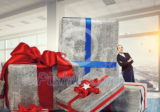 Young businesswoman among pile of gift boxes. Mixed media