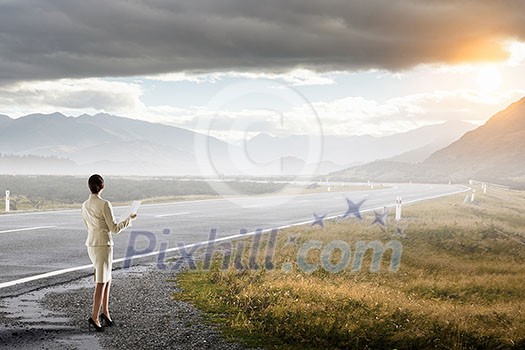 Elegant businesswoman on road standing with back and looking ahead. Mixed media Elegant businesswoman on road standing with back and looking ahead. Mixed media