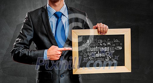 Handsome businessman holding wooden frame with business sketches. Mixed media Handsome businessman holding wooden frame with business sketches. Mixed media