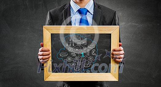 Handsome businessman holding wooden frame with business sketches. Mixed media Handsome businessman holding wooden frame with business sketches. Mixed media