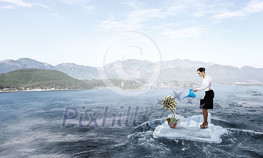 Young attractive businesswoman watering plant in pot with can. Mixed media Young attractive businesswoman watering plant in pot with can. Mixed media