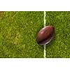 Rugby brown ball on green field grass