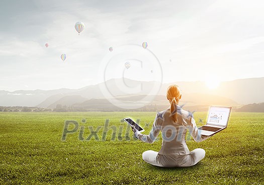 Elegant businesswoman sitting in lotus pose on green grass. Mixed media Elegant businesswoman sitting in lotus pose on green grass. Mixed media