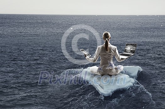 Businesswoman in lotus pose floating on ice block. Mixed media Businesswoman in lotus pose floating on ice block. Mixed media