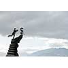 Businessman with laptop in hands running on stone stairway. Mixed media