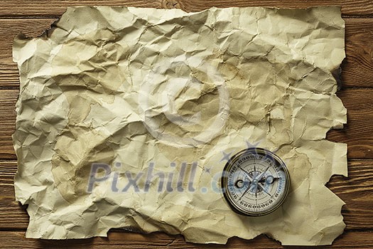 Old crumpled paper and compass on wooden table Old crumpled paper and compass on wooden table