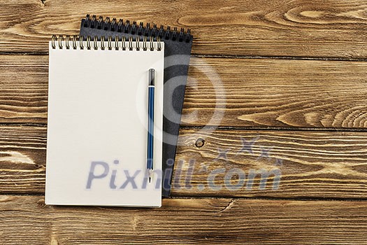 Top view of two notepads with pencil on wooden background Top view of two notepads with pencil on wooden background