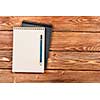 Top view of two notepads with pencil on wooden background