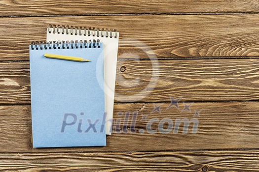Top view of two notepads with pencil on wooden background Top view of two notepads with pencil on wooden background