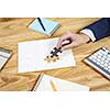 Hand of businesswoman completing puzzle with missing piece