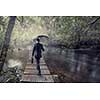 Businessman with umbrella walking alone in forest. Mixed media