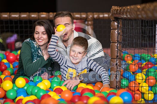 happy family enjoying free time young parents and kids playing in the pool with colorful balls at childrens playroom happy family enjoying free time young parents and kids playing in the pool with colorful balls at childrens playroom