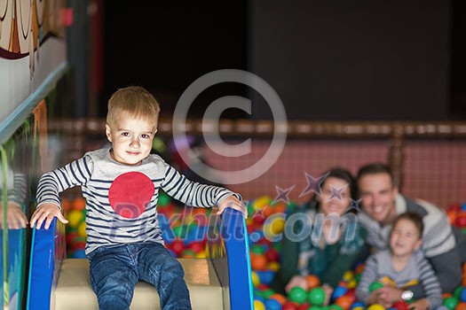 happy family enjoying free time young parents and kids playing in the pool with colorful balls at childrens playroom happy family enjoying free time young parents and kids playing in the pool with colorful balls at childrens playroom