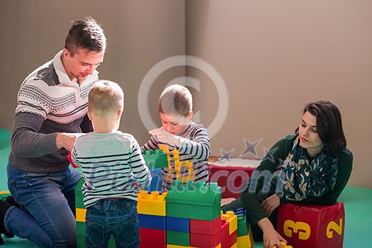 happy family enjoying free time young parents and kids having fun while playing together at childrens playroom happy family enjoying free time young parents and kids having fun while playing together at childrens playroom