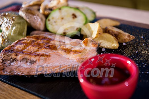 Juicy grilled steak with vegetables on a wooden board Juicy grilled steak with vegetables on a wooden board