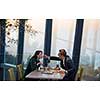 young happy loving couple enjoying romantic dinner while celebrating Valentines day near the window at luxury restaurant