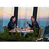 young happy loving couple enjoying romantic dinner while celebrating Valentines day near the window at luxury restaurant