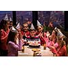 young happy boy and group of his friends having birthday party with a night city through the windows in the background