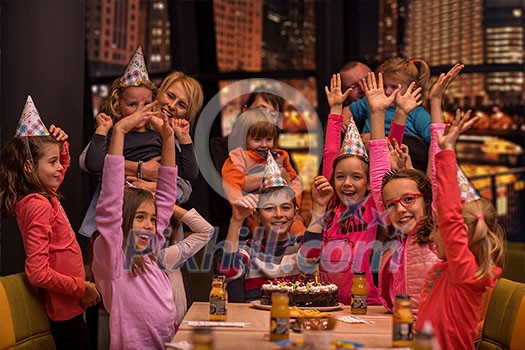 young happy boy and group of his friends having birthday party with a night city through the windows in the background young happy boy and group of his friends having birthday party with a night city through the windows in the background