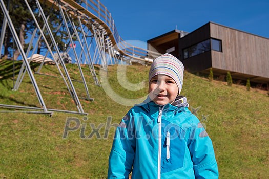 portrait of a young boy with blue jacket and hat on sunny day in nature under alpine coaster portrait of a young boy with blue jacket and hat on sunny day in nature under alpine coaster