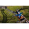 Excited young mother and son driving on alpine coaster while enjoying beautiful sunny day in the nature