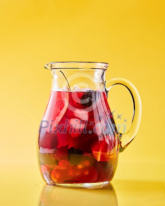 Freshly made berry fruit drink in a glass jug on a yellow background with copy space. Summer vitamin beverage Freshly made berry fruit drink in a glass jug on a yellow background with copy space. Summer vitamin beverage
