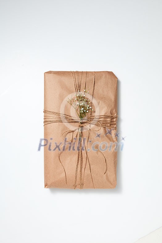Present box wrapped craft paper with flowers and rope on a light background with space for text. Concept for birthday. Flat lay Present box wrapped craft paper with flowers and rope on a light background with space for text. Concept for birthday. Flat lay