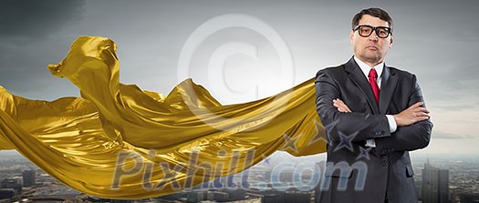 Aged businessman in golden cape with arms crossed on chest. Mixed media Aged businessman in golden cape with arms crossed on chest. Mixed media