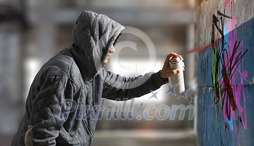 Man hiding face with hoodie and spraying paint with balloon. Mixed media Man hiding face with hoodie and spraying paint with balloon. Mixed media