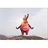 Young cheerful businesswoman flying on pink piggy bank. Mixed media