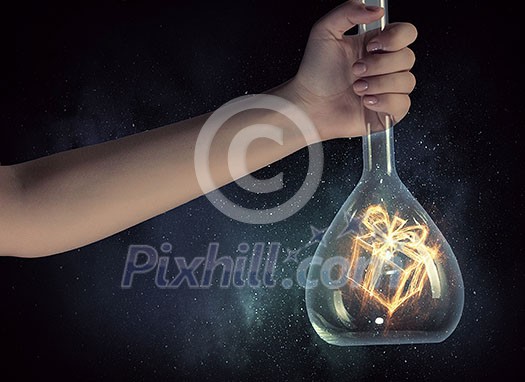 Close up of human hand holding test tube with gift concept. Mixed media Close up of human hand holding test tube with gift concept. Mixed media