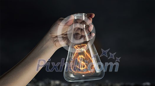 Close up image of human hand holding test tube with money symbol Close up image of human hand holding test tube with money symbol