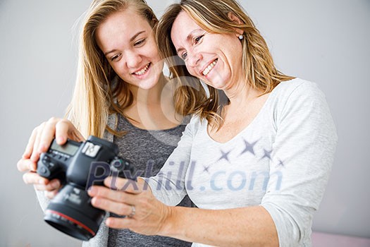 Mother and daughter taking photos and checking them on a modern digital DSLR camera Mother and daughter taking photos and checking them on a modern digital DSLR camera