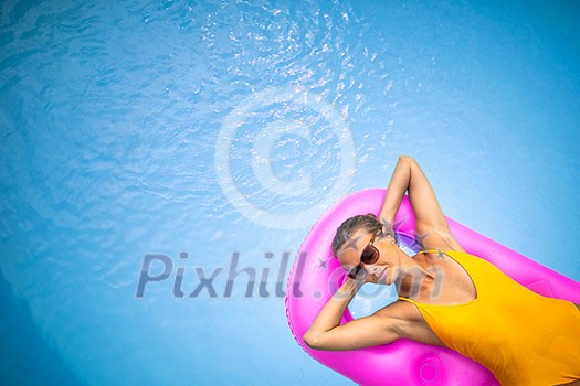 Young Beautiful Suntanned Woman wearing sunglasses relaxing next to a Swimming Pool on a lovely Summer Day Young Beautiful Suntanned Woman wearing sunglasses relaxing next to a Swimming Pool on a lovely Summer Day