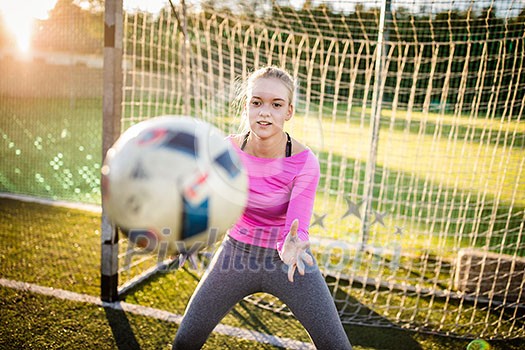 Teen female goalie catching a shot during a soccer game Teen female goalie catching a shot during a soccer game