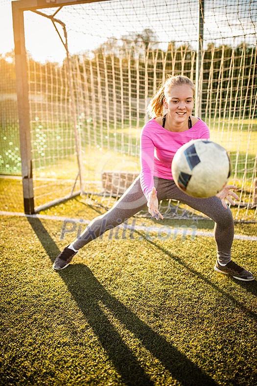 Teen female goalie catching a shot during a soccer game Teen female goalie catching a shot during a soccer game