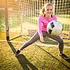 Teen female goalie catching a shot during a soccer game