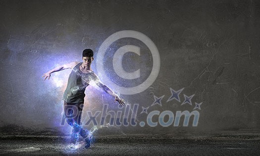 Breakdancer in jump in empty concrete room. Mixed media Breakdancer in jump in empty concrete room. Mixed media
