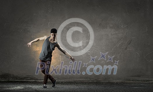 Breakdancer in jump in empty concrete room. Mixed media Breakdancer in jump in empty concrete room. Mixed media