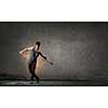 Breakdancer in jump in empty concrete room. Mixed media